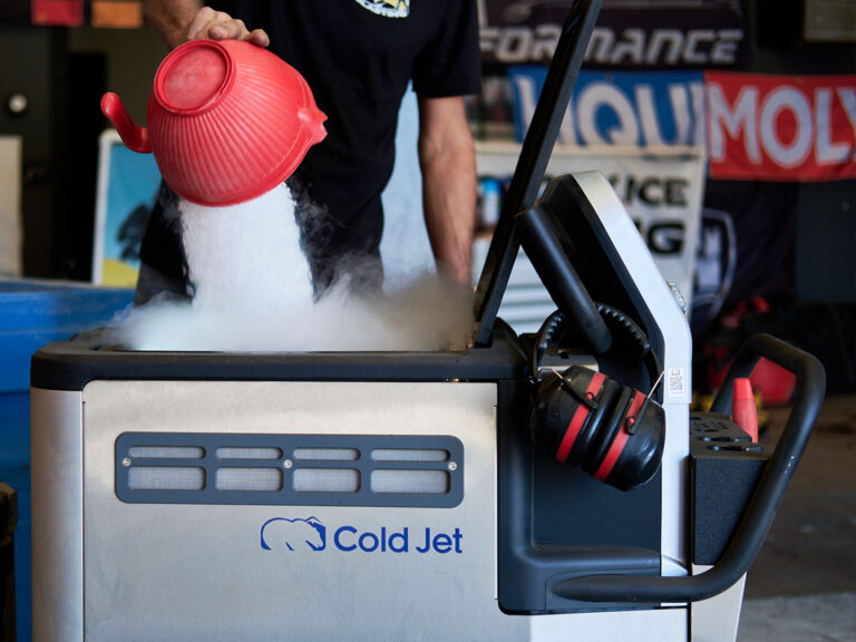 technician pouring dry ice pellets into a Cold Jet blasting machine in a workshop environment