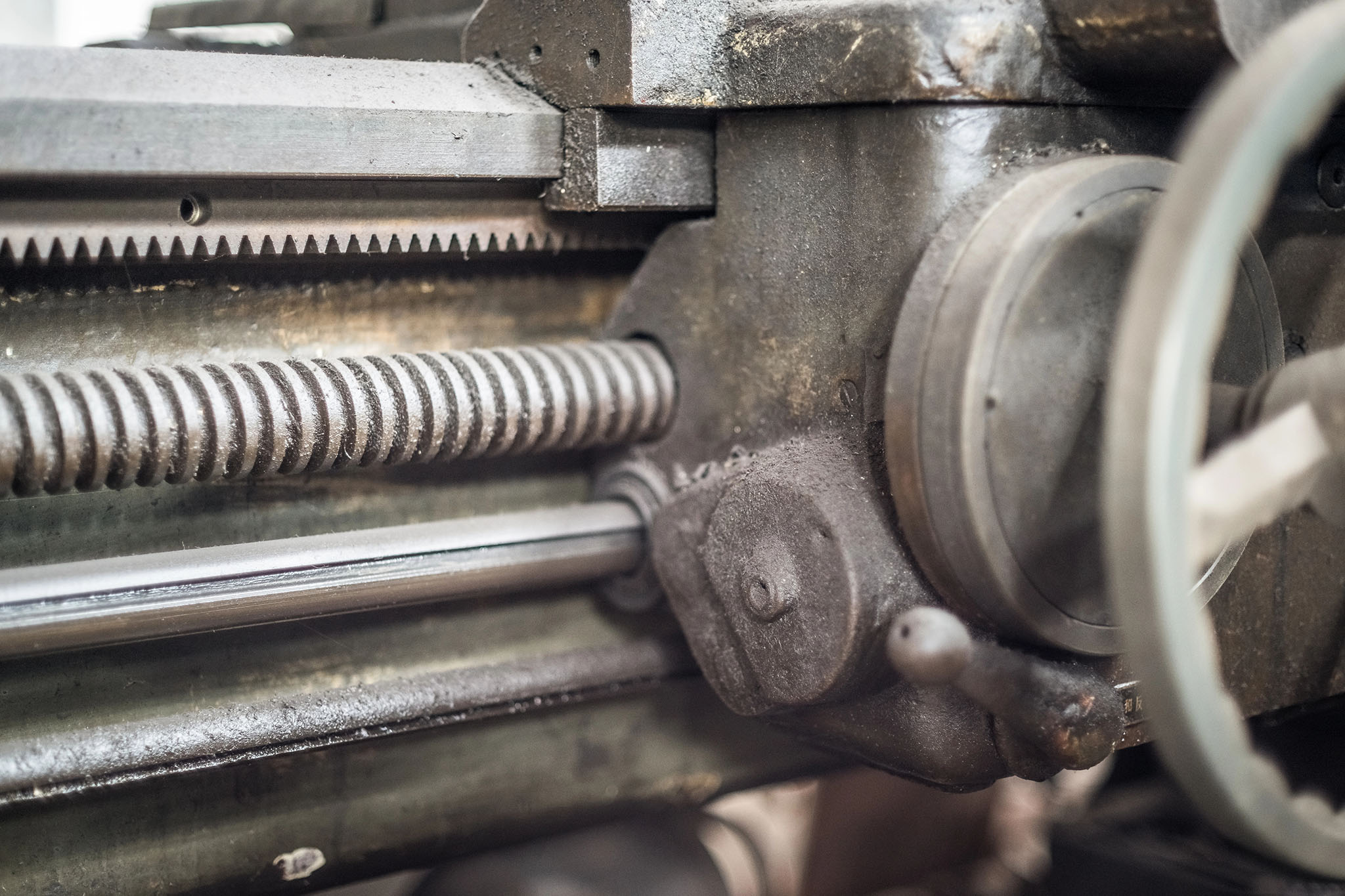 close-up of an industrial machine with a metal gear and threaded rod, showing mechanical detail and surface wear